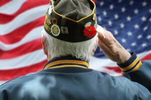 A white hair retired veteran salutes the American flag