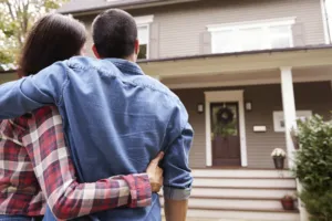 a couple looks at their home from the sidewalk