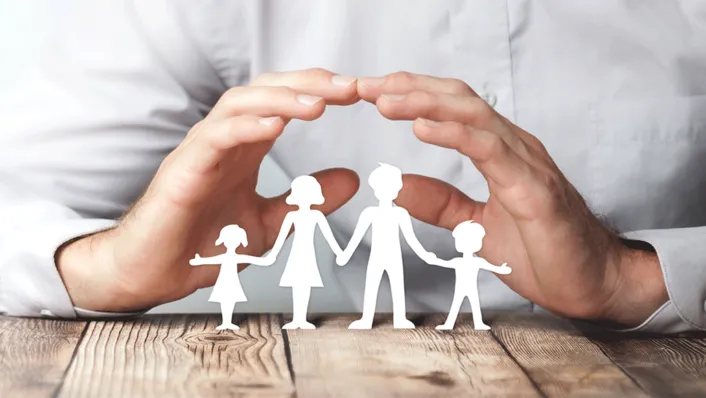 Manos sobre una mesa haciendo un arco sobre un adhesivo del contorno de una familia