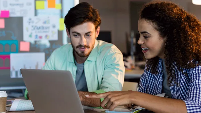 Pareja usando una computadora portátil en la cocina, revisando las finanzas