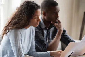 a couple stares at a computer screen, looking worried