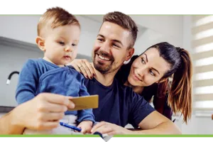 Smiling couple, looking at their young toddler, father holding credit card