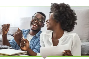 Happy couple laughing while working on finances in living room