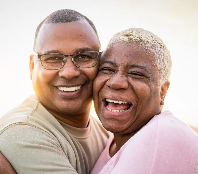 Happy senior couple embracing during sunset outside, facing the camera