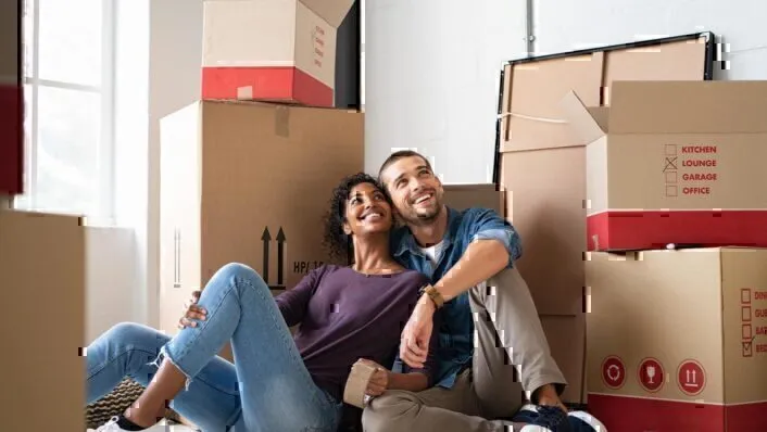 Una pareja joven sentada frente a cajas vacías después de mudarse.