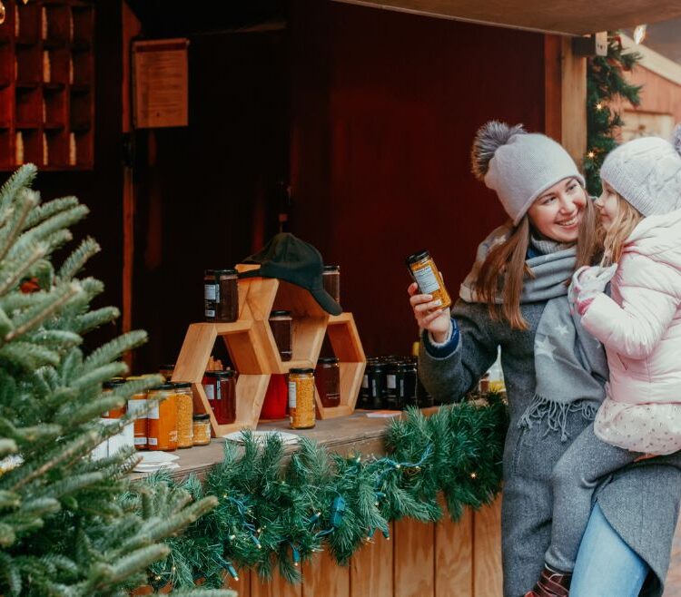 Woman holiday shopping with child in front of store window with christmas tree