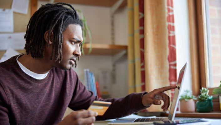 Student managing loan payments online with laptop and credit card