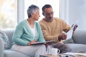 Older diverse couple looking at documents on couch