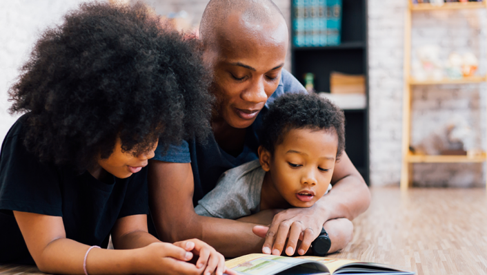 Dad with two kids reading a book.