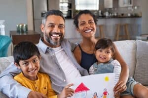 Family of four sitting on light gray couch.