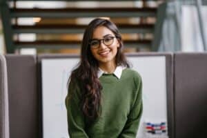 Southeast Indian woman wearing a green sweater smiling.
