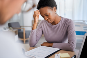 black woman pensively looking at her medical bill