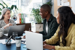 a group of people sitting at a desk talking to each other