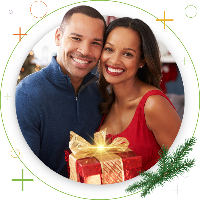black couple smiling posing for holiday photo with a red gift box and gold bow tie
