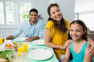 a family of three having dinner and smiling at the camera