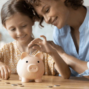 mom teaching daughter how to save money using a piggy bank