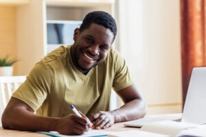 black man sitting at a desk filling out paper applications