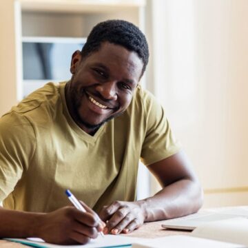 black man sitting at a desk filling out paper applications