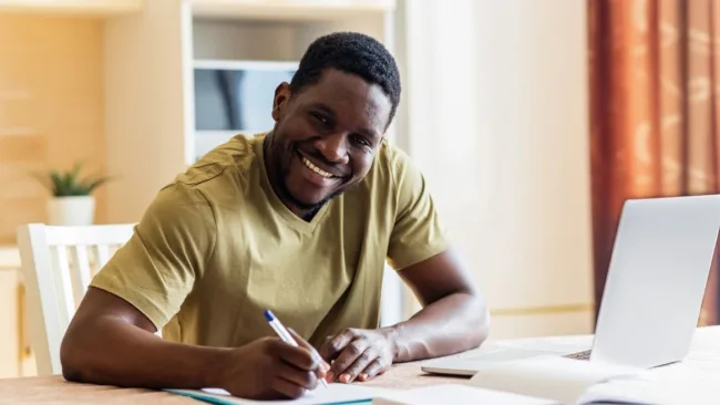 Hombre negro sentado en un escritorio llenando solicitudes en papel