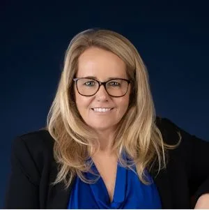 Lisa Musch in corporate attire with glasses smiling at camera