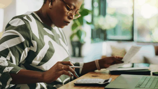 woman in green and white shirt punching numbers on a calculator