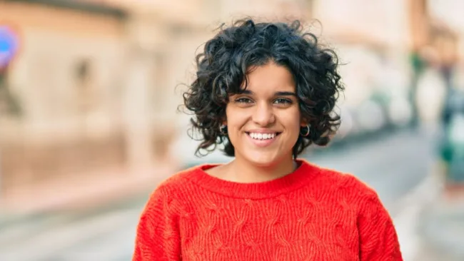 Mujer sonriente de pie en la calle.