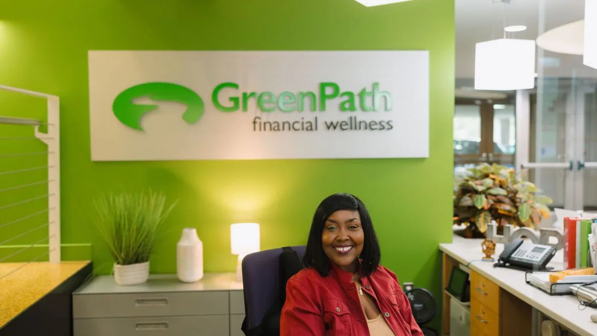 Hope sitting at the front desk with the GreenPath logo behind.
